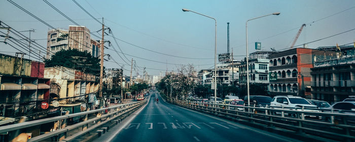 Cars on road against sky in city