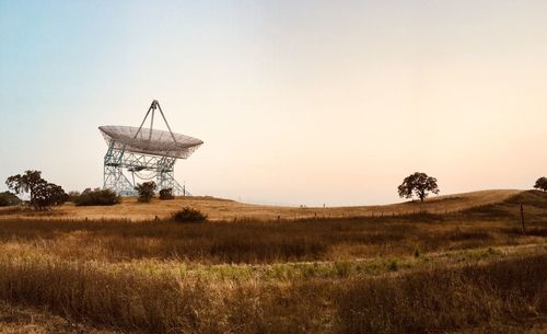 Communications tower on land against clear sky