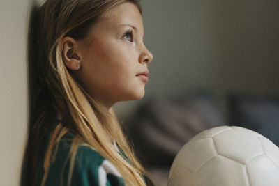 Contemplative girl with sports ball looking away at home