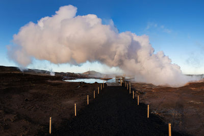 Panoramic view of smoke emitting from land against sky