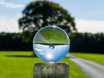 Close-up of crystal ball on wooden post on field