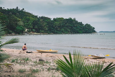 Scenic view of man and kayaks on lakeshore