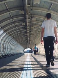 Rear view of people walking on bridge