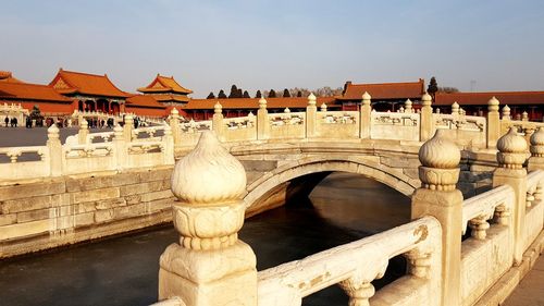 Arch bridge over river against palace - forbidden city in bejing