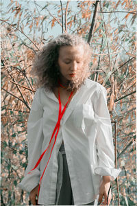 Teenage girl with umbrella standing by tree