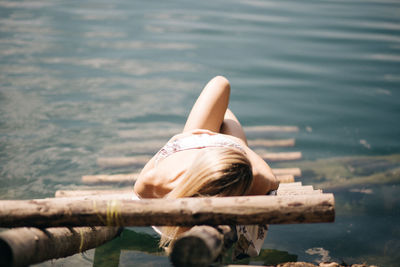 Rear view of woman lying in lake