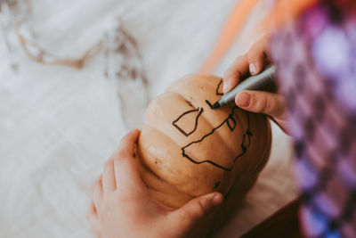 Little preschooler boy in festive halloween costume drawing pumpkin lantern jack at home