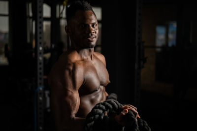 Shirtless athlete holding rope in gym