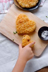 Cropped hand of person touching deep fried heard shape stack on cutting board over table