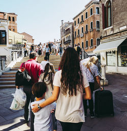 Rear view of people walking on street in city