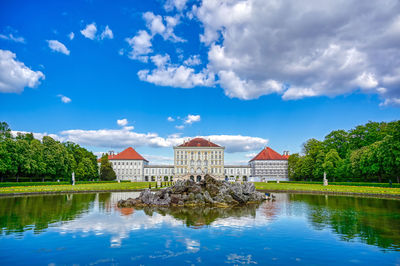 Reflection of buildings in lake against cloudy sky