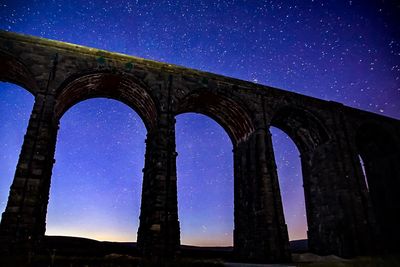 Low angle view of arch against clear sky at night