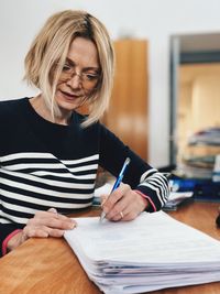 Mature woman writing on document