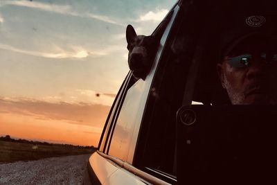 Portrait of man in car against sky during sunset