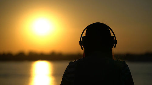 Rear view of silhouette man standing against sky during sunset