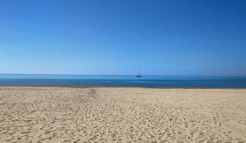 Scenic view of beach against clear blue sky