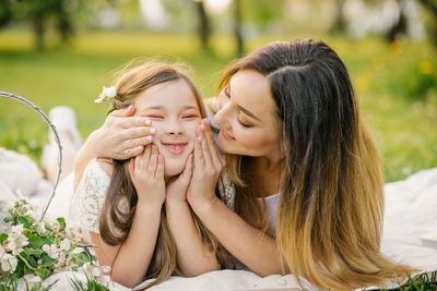 Happy mom and daughter relax lifestyle in the park in the summer and make grimaces