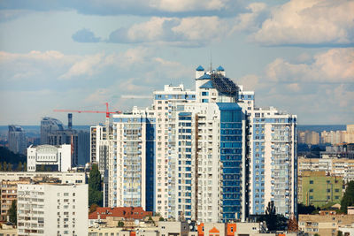 Solar panels on the roof of multi-storey building in the background of residential area of the city.