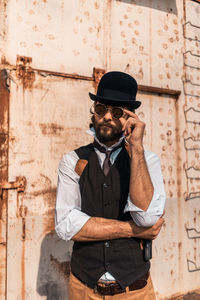 Man wearing hat standing against wall