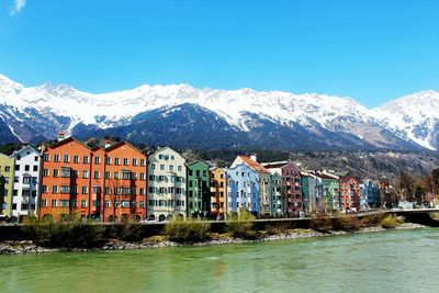Buildings by mountains against clear blue sky