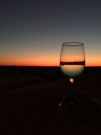 Close-up of wineglass against clear sky during sunset
