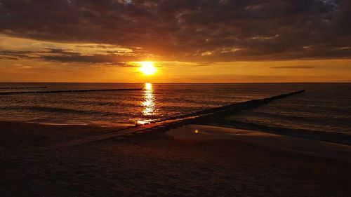 Scenic view of sea against dramatic sky during sunset