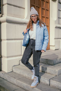 Portrait of young woman standing against building