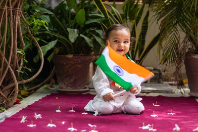 Cute toddler holding indian tricolor flag in traditional cloth with innocent facial expression