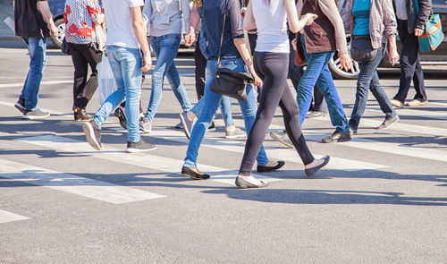 Low section of people walking on street in city