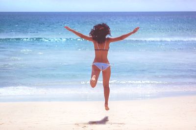 Full length of woman walking at beach against sky