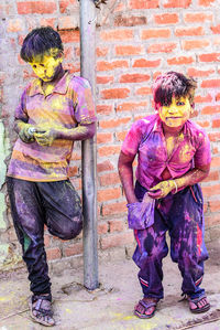 Full length of children covered in multi colored powder paint