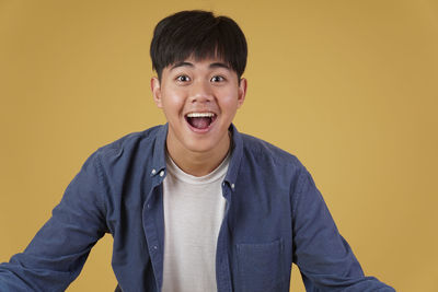 Portrait of smiling man against yellow background