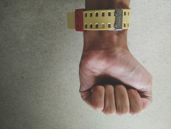 Cropped hand of man wearing wristwatch against wall