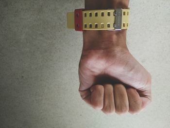 Close-up of hand holding camera against wall