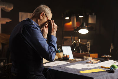 Side view of young man using mobile phone while sitting on table