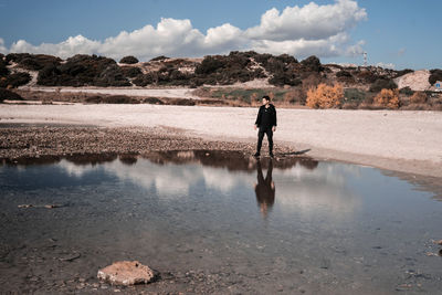 Rear view of man walking at beach against sky