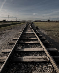 Surface level of railroad tracks on field against sky