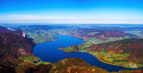 Aerial view of sea and mountains against blue sky