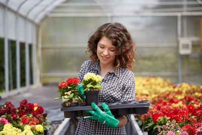 Smiling young woman holding flowering plants