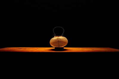 Close-up of lamp on table against black background