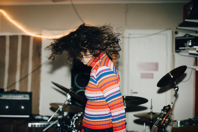 Side view of young woman dancing by drum kit at rehearsal studio