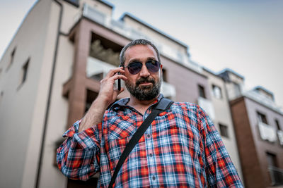 Portrait of handsome businessman with sunglasses and plaid shirt . he talks over his mobile phone
