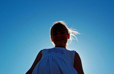 Low angle view of girl with blue clear sky