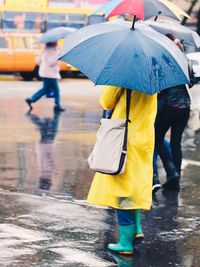 Low section of people walking on wet road during rainy season