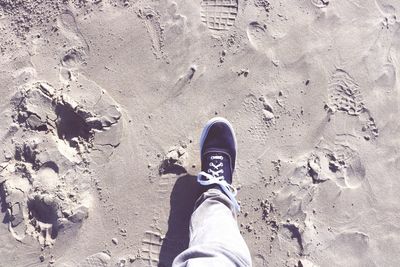 Low section of man standing on sand at beach