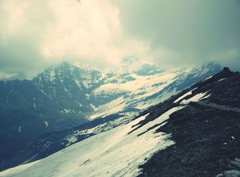 Scenic view of snowcapped mountains against cloudy sky