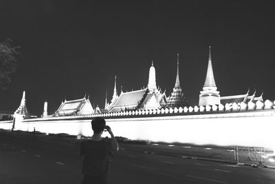 Rear view of woman on temple against sky at night