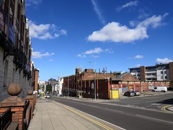 Road by buildings in city against sky