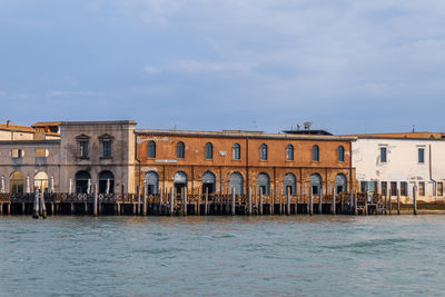 Buildings by river against sky