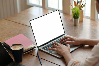 Midsection of woman using laptop on table